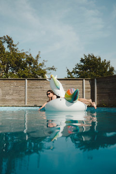Woman on inflatable unicorn in swimming-pool