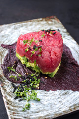 Gourmet fish tartar raw from tuna fillet with hashed avocado, umebashi and Japanese spice as closeup on modern design plate