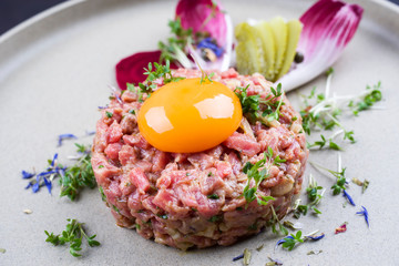 Gourmet Tartar roh vom Rinderfilet mit Eigelb und Gemüse als closeup auf einem Modern Design Teller