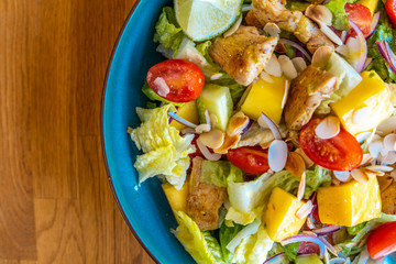 Top view of a homemade chicken salad with mango, tomatoes and fresh onion