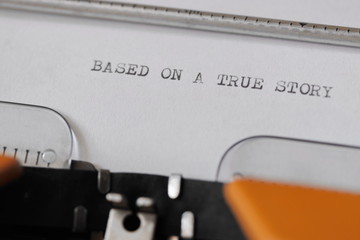 Close up footage of ˝BASED ON A TRUE STORY˝ written on a paper, on an old typewriter with capital...