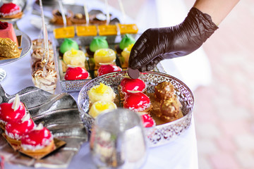 Hands in black gloves serves sweets. Catering