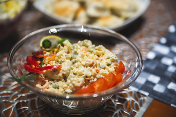 Holiday salad with cooked vegetables, mayonnaise and mustard. Traditional slavic salad made for christmas with other dishes in the background. Strong bokeh.