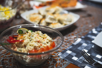 Holiday salad with cooked vegetables, mayonnaise and mustard. Traditional slavic salad made for christmas with other dishes in the background. Strong bokeh.