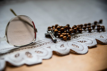 Wooden rosary and glasses of an elder on the white blanket, on the wooden table. Orthodox old believer concept background.