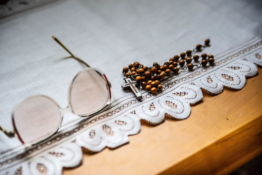 Wooden rosary and glasses of an elder on the white blanket, on the wooden table. Orthodox old believer concept background.