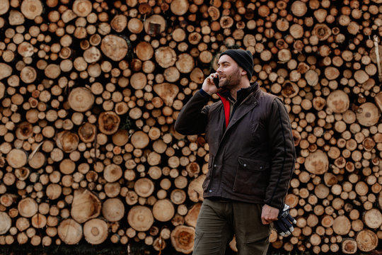 Man standing in front of stack of logs