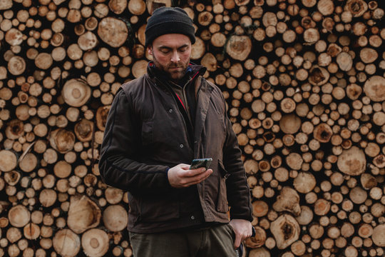 Man standing in front of stack of logs