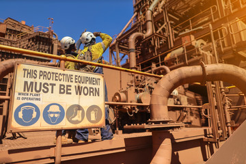 Personnel protective equipment (PPE) must be worn sign with defocused of construction workers...