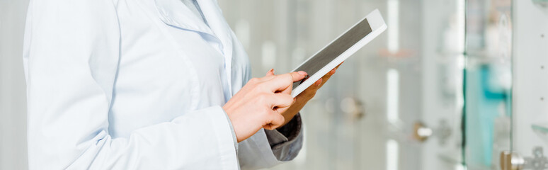 Obraz premium Cropped view of pharmacist using digital tablet in pharmacy, panoramic shot