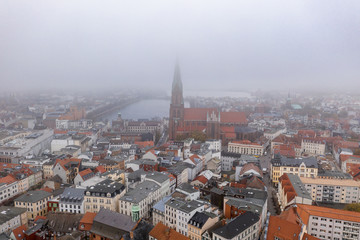 Fototapeta na wymiar Aerial drone shot view of Schwerin Cathedral by the lake amist heavy morning fog haze smog