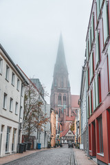 Naklejka premium Street view of clock tower of schwerin cathedral with heavy fog in Schwerin near Hamburg, Germany