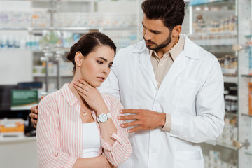 Pharmacist beside woman with throat pain in apothecary