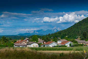 Fototapeta na wymiar View of a mountain town, slopes covered with forest and mountain peaks in the distance a blue sky with clouds.Allinges town.Haute-Savoie in France.