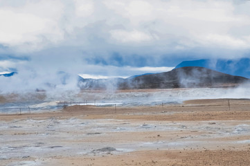 Mudpots in the geothermal area, al lot of steam, Hverir, Iceland. The area is multicolored and cracked.