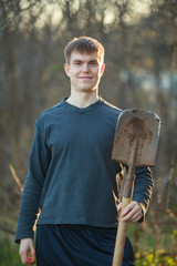 Agronomist handsome strong man with shovel on  background of flower beds