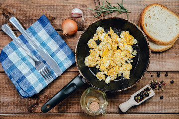 Top view on Scrambled eggs in a pan on a wooden countertop. The concept of preparing a meal of eggs, scrambled eggs.