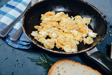 Scrambled eggs in a pan on a stone counter. The concept of preparing a meal of eggs, scrambled eggs.