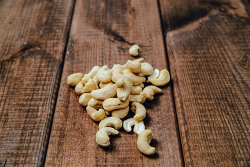 Cashews on a wooden background. The concept of eating nuts, giving them to a meal.