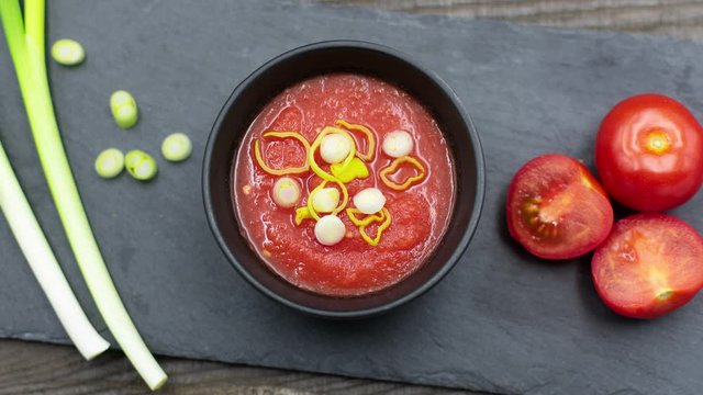Tomatensuppe mit Knoblauch, Frühlingszwiebeln und Basilikum auf Schieferplatte angerichtet