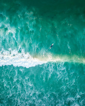Aerial view of lonely surfer over agitated blue water, Cape Town, South Africa.
