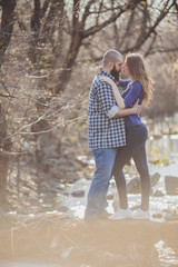 young and stylish couple standing near water in park