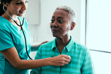 Nurse listening to stethoscope on patient's chest