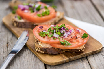 Some Tomato Sandwich on a vintage wooden table (selective focus; close-up shot)