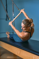 Young girl doing pilates exercises with a reformer bed. Beautiful slim fitness trainer on reformer...
