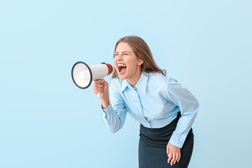 Young businesswoman with megaphone on color background