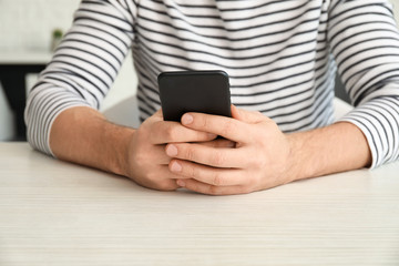 Man with mobile phone sitting at table, closeup
