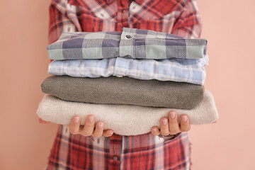 Young woman with clean laundry on color background, closeup