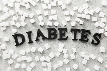 Word DIABETES and sugar cubes on light background