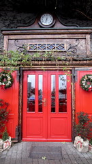 Red large wooden door with a clock above the entrance