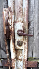 Handle and rusty lock in wooden wicket door close-up