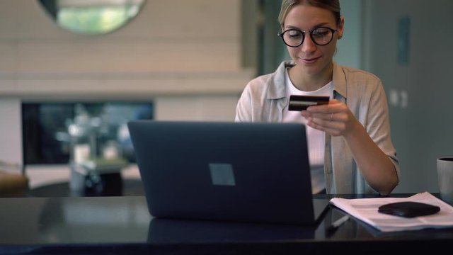 Positive millennial female doing online ticketing happy from order with sale discount using debit credit card for online transfer via modern laptop computer, concept of banking operation
