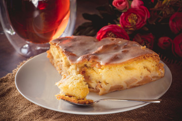 A piece of apple pie on a white plate on a background of pink flowers