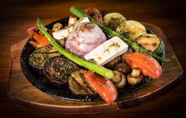 Grilled vegetables on cutting board on dark wooden background