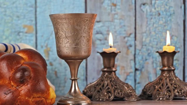 Shabbat eve table with covered challah bread, candles and cup of wine.