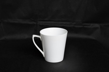 Obraz na płótnie Canvas A white porcelain cup is isolated on a black background.