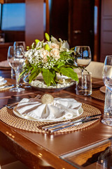 Vertical shot of a dinner table with plates and wine glasses on the yacht