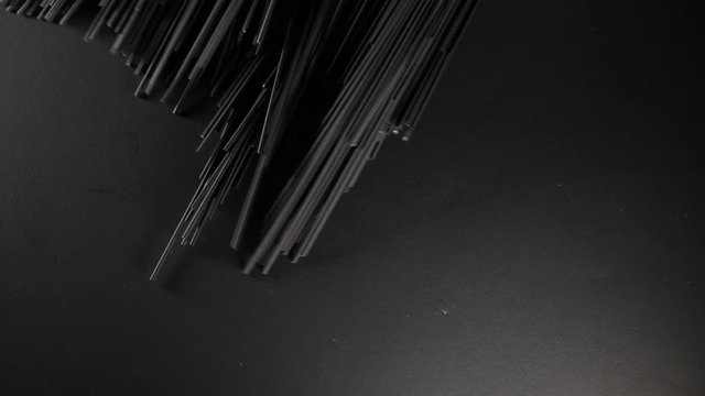 Man puts cuttlefish ink spaghetti pasta on the dark black background, close up video