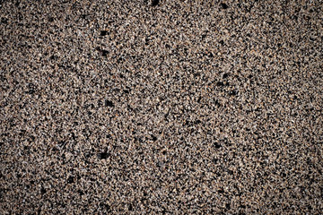 Coarse sand grains and small pebbles, finely ground minerals on an ocean beach, top view, close up detail.