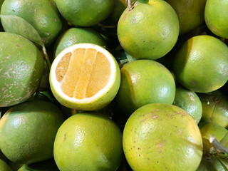 Green oranges in a metal basket for sale, Background for texture