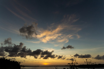 Sunset in the lagoon. The sun is hidden behind the clouds. Golden clouds in the sky. The water reflects the light of the sun.