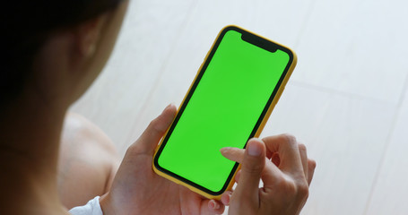 Woman use of mobile phone with green screen at home