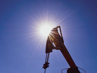 Head counterweight oil pump jack backlit. Oil equipment against