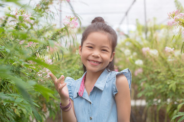 Toddler asia girl playing in flower field. Child gardening. Kid in the backyard. Children working in the garden. Kids taking care of plants. First spring blossoms.