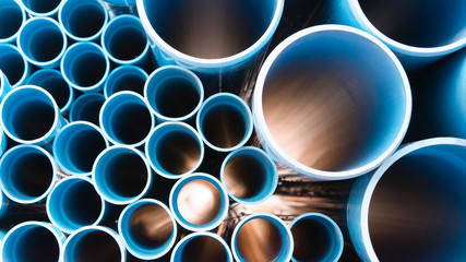Blue plastic pipes used in construction site.Blue PVC water pipe in storage.Packaged blue plastic water pipes at warehouse. - obrazy, fototapety, plakaty