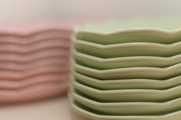 Platos de vajilla de cerámica verdes y rosas apilados en la alacena
